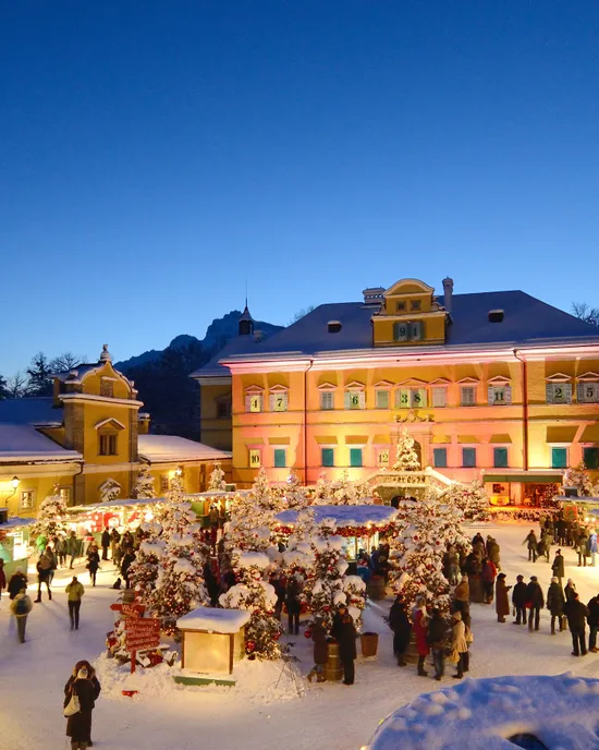 Mercatino di Natale festivo con bancarelle decorate e luci in un cortile innevato al crepuscolo